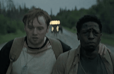 Two Men Are Walking Down A Road And One Has A Bandage On His Forehead GIF