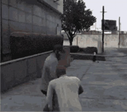 Two Men Are Walking Down A Sidewalk In Front Of A Building And A Tree GIF