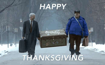 Two Men Are Walking Down A Street Carrying A Trunk That Says Happy Birthday Thanksgiving GIF
