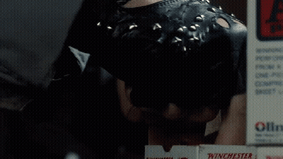 Two Men Are Working In A Gun Shop With An Exit Sign Above Them GIF