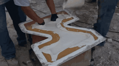 Two Men Are Working On A Piece Of Plastic That Looks Like A Cross GIF
