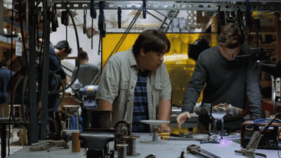 two men are working on a project in a workshop and one of them is looking at a box that says welding