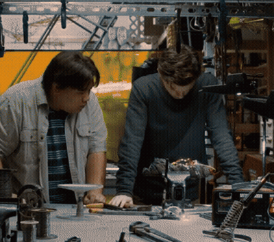 Two Men Are Working On A Project In A Workshop With A Soldering Iron That Says ' A ' On It GIF