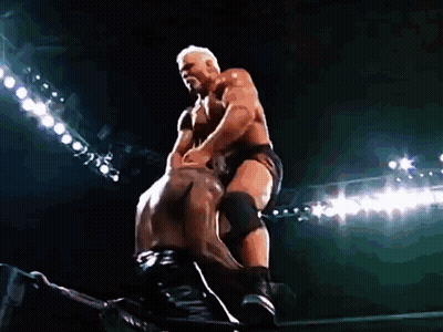 Two Men Are Wrestling In A Dark Stadium With Lights Behind Them . GIF