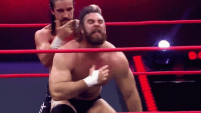Two Men Are Wrestling In A Ring And One Of Them Is Wearing A Bandage On His Chest . GIF