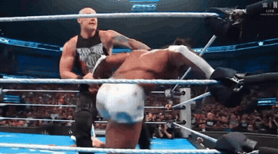 two men are wrestling in a ring and one of them is wearing a tank top that says smack down