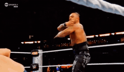 Two Men Are Wrestling In A Ring With A Crowd Watching . One Of The Men Is Pointing At The Camera . GIF