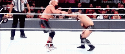 Two Men Are Wrestling In A Ring With A Referee In The Background . GIF