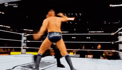 Two Men Are Wrestling In A Ring With A Referee In The Background . GIF