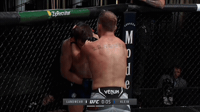 Two Men Are Wrestling In A Ufc Ring With A Howler Head Sign In The Background GIF