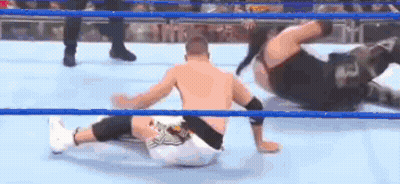 Two Men Are Wrestling In A Wrestling Ring And One Is Laying On The Ground . GIF