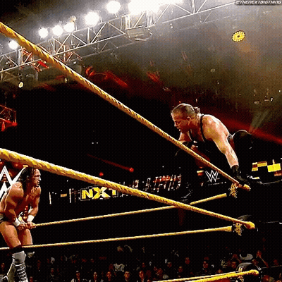 Two Men Are Wrestling In A Wrestling Ring And One Of Them Is Jumping Over Ropes . GIF
