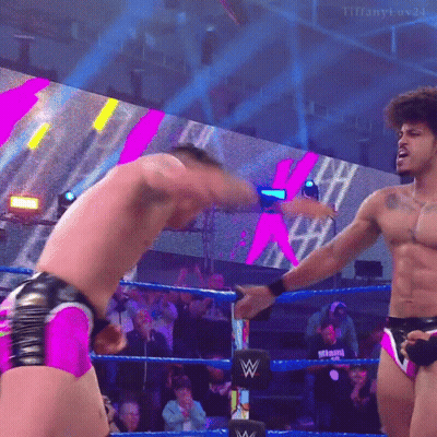 Two Men Are Wrestling In A Wrestling Ring And One Of Them Is Wearing Pink Shorts . GIF