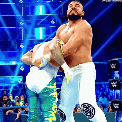 Two Men Are Wrestling In A Wrestling Ring And One Of Them Is Wearing White Pants GIF