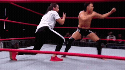 Two Men Are Wrestling In A Wrestling Ring . GIF