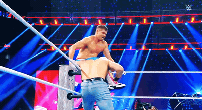 Two Men Are Wrestling In A Wrestling Ring On A Stage With A Lot Of Lights . GIF