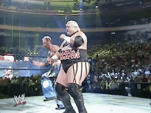 Two Men Are Wrestling In A Wrestling Ring With A Crowd In The Background . GIF