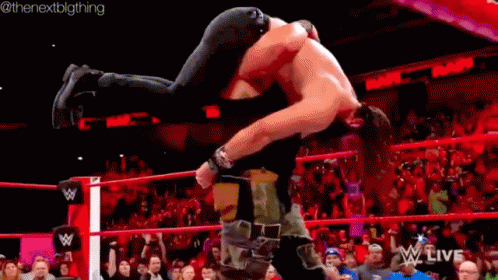 Two Men Are Wrestling In A Wrestling Ring With A Crowd In The Stands Watching . GIF