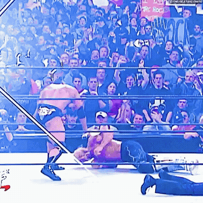 Two Men Are Wrestling In A Wrestling Ring With A Crowd Watching . GIF