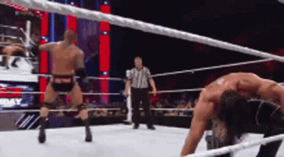 Two Men Are Wrestling In A Wrestling Ring With A Referee In The Background GIF