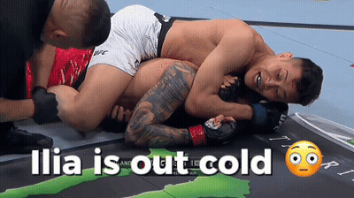 Two Men Are Wrestling On A Mat And The Words Ilia Is Out Cold Are Above Them GIF