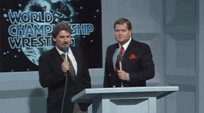 Two Men At Podium With World Champion Wrestling Screen GIF