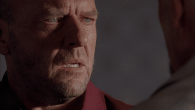 Two Men At Table In Dark Room With Boxes GIF