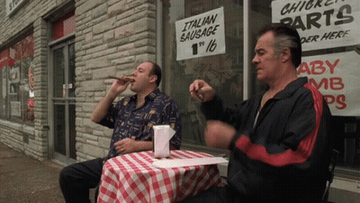 Two Men At Table With Italian Sausage Sign GIF