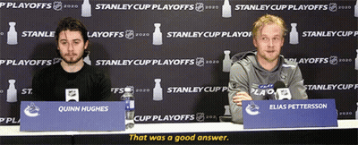 Two Men At Table With Quinn Hughes Sign GIF