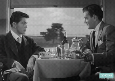 Two Men At Table With Wine Bottle And TCM Logo GIF