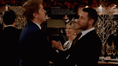 Two Men Beside ITV Sign GIF