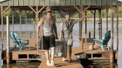 Two Men Carrying Cooler On Dock GIF