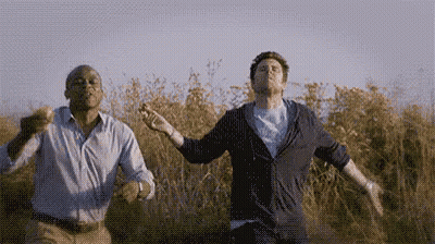Two Men Dancing In A Field With Arms Outstretched GIF