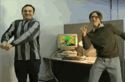 Two Men Dancing In Front Of A Computer Monitor GIF