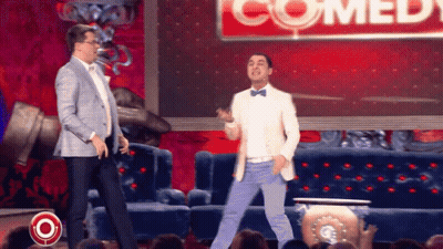 Two Men Dancing In Front Of Comedy Sign GIF