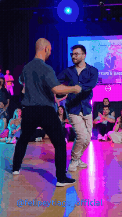 Two Men Dancing In Front Of Felipe Tiago Screen GIF