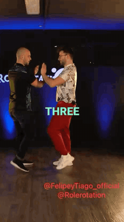 Two Men Dancing In Front Of Sign Saying Three GIF