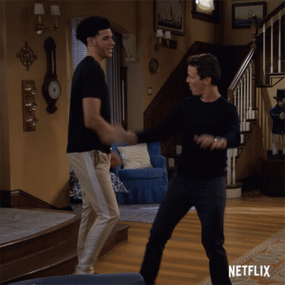 Two Men Dancing In Living Room With Netflix Logo GIF