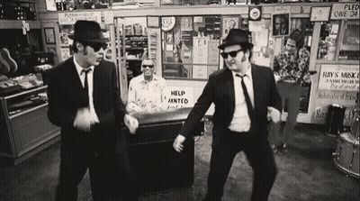 Two Men Dancing In Store With Help Wanted Sign GIF