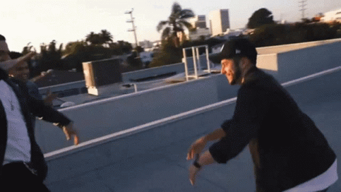 Two Men Dancing On Rooftop One Wearing New Era Hat GIF