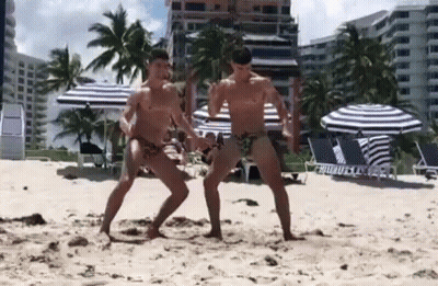 Two Men Dancing Shirtless On Beach GIF