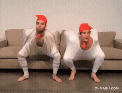 Two Men Dressed As Chickens Squatting On Couch GIF