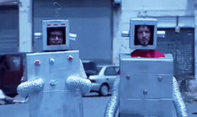 Two Men Dressed As Robots Walking Down Street GIF