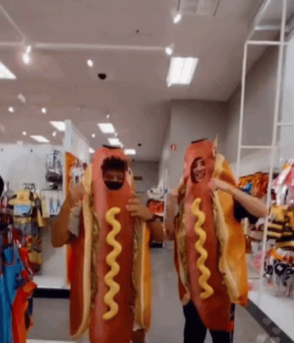 Two Men Dressed Up As Hot Dogs With Mustard On Them GIF