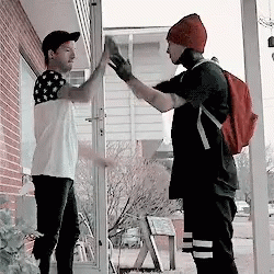 Two Men Giving Each Other A High Five While Standing On A Porch GIF