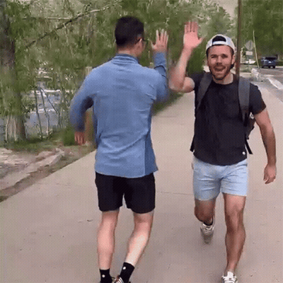 Two Men High Fiving On Sidewalk GIF