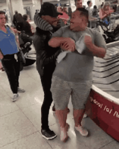 Two Men Hugging At Airport Woman Watches GIF