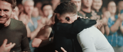 Two Men Hugging In Front Of A Crowd Of People GIF