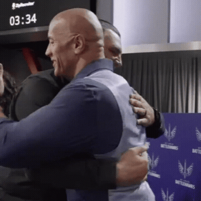 Two Men Hugging In Front Of A Wall That Says Battlehawks GIF
