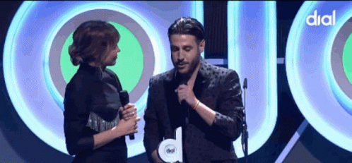 Two Men Hugging In Front Of Dial Sign GIF